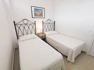 2 Betten in einem Zimmer mit weißen Wänden in der Unterkunft Bayuca 107 Yumbo Center By Pride Holiday Rentals in Maspalomas