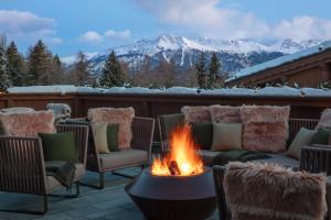 uma fogueira num pátio com montanhas cobertas de neve em Guarda Golf Hotel & Residences em Crans-Montana