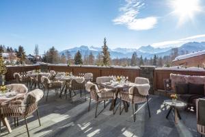 um pátio com mesas e cadeiras com montanhas ao fundo em Guarda Golf Hotel & Residences em Crans-Montana