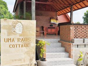 ein Schild vor einem Gebäude mit einem Haus in der Unterkunft Uma Raos Cottage in Ubud