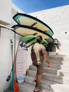 un hombre está de pie en las escaleras con su tabla de surf en Turismo do Seculo, en Estoril