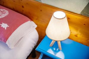 a lamp on a blue table next to a bed at Residence Larice Bianco App n3 in Campodolcino