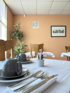 une table avec de l'argenterie sur un tissu de table blanc dans l'établissement Hôtel Restaurant d'Occitanie, à Toulouse