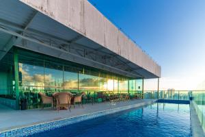 un edificio con mesas y sillas junto a una piscina en Sotero Hotel by Castelo Itaipava, en Salvador