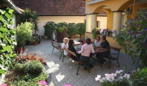 eine Gruppe von Menschen, die an einem Tisch im Innenhof sitzen in der Unterkunft Ferienhof Uhudler-Arkaden in Stegersbach