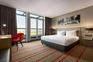 Ramada by Wyndham Amsterdam Airport Schiphol في باتهوفيدورب: غرفة في الفندق بها سرير ومكتب ونافذة