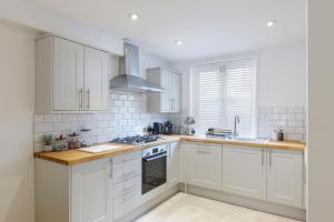 een keuken met witte kasten en een fornuis met oven bij Luxury 5 Bedroom House By The Sea in Brighton & Hove