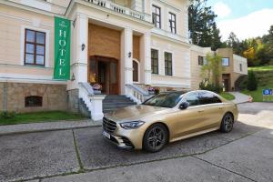 um carro dourado estacionado em frente a um edifício em Hotel Château Cihelny em Karlovy Vary