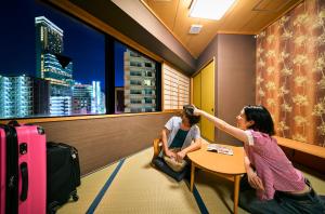 a woman sitting at a table cutting a mans hair at COGO TENNOJI in Osaka