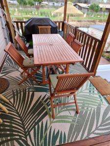 - une table et des chaises en bois sur une terrasse couverte avec un tapis dans l'établissement Mobil home tout confort au Camping Les Viviers, Cap Ferret, à Claouey