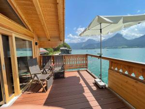 a wooden deck with an umbrella and chairs on the water at Hotel Zimmerbräu in St. Wolfgang