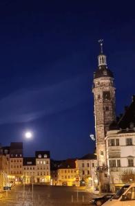 uma torre do relógio com uma cruz em cima à noite em Haus Heiken Apartment Sonnenblume em Altenburg