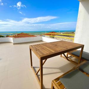 una mesa de madera en un balcón con vistas al océano en Ericeira Panoramic Sea View Apartments, en Ericeira