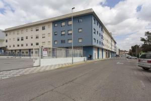 una calle vacía frente a un gran edificio en Apartamento EL MIRADOR, recepción 24 h, piscina, wifi y parking interior, en Bormujos