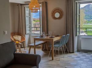 een eetkamer met een tafel, stoelen en ramen bij La Perle du Lac 3* - VUE LAC in Annecy