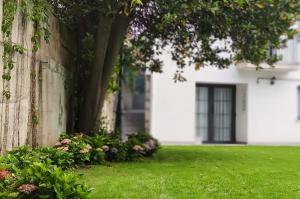 een huis met een tuin met groen gras en bloemen bij Le Petit Apartamentos in Santander