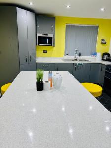 una cucina con bancone bianco e pareti gialle di Room in Oldham, Manchester a Oldham