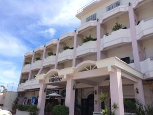 a large white building with potted plants on it at Holiday Saipan Hotel in Saipan