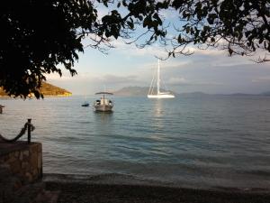 deux bateaux flottant sur un lac avec des montagnes en arrière-plan dans l'établissement Mouria Pension Rooms & Studios, à Ancient Epidavros