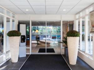 a lobby with two large vases with plants in them at Novotel Maastricht in Maastricht