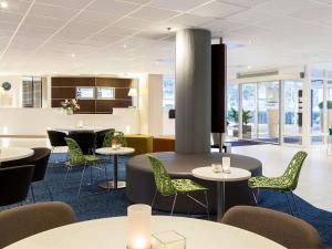 a dining room with tables and chairs and a lobby at Novotel Maastricht in Maastricht