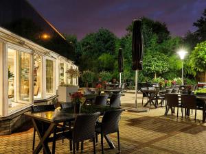 a patio with tables and chairs and a restaurant at Novotel Maastricht in Maastricht