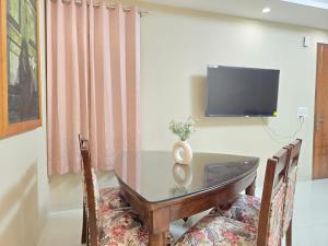 une salle à manger avec une table en verre et une télévision dans l'établissement Homlee-Saket Anupam Stylish 3BHK in South Delhi, à New Delhi