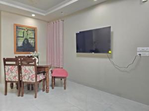 - un salon avec une table et une télévision murale dans l'établissement Homlee-Saket Anupam Stylish 3BHK in South Delhi, à New Delhi