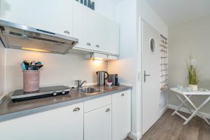 a kitchen with white cabinets and a sink at Möwennest App 18 in Wenningstedt