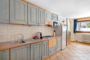 a kitchen with white cabinets and a sink at Residence Larice Bianco App n3 in Campodolcino