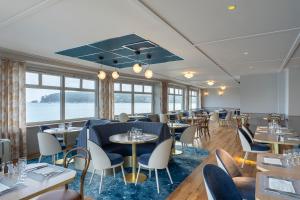 een restaurant met tafels, stoelen en ramen bij Hôtel Morgat Le Grand Hôtel De La Mer in Crozon