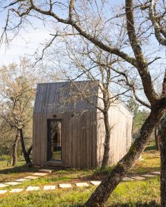 a small wooden house in a field with trees at Refugio do Carrascal in Tomar