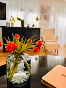 een vaas gevuld met rode bloemen zittend op een tafel bij Boutique Apartment Lola in Fažana