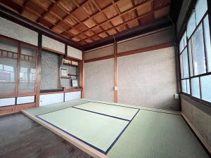 ein leeres Zimmer mit einem Tisch in einem Zimmer mit Fenstern in der Unterkunft Hostel Miyagawa by Murasaki in Takayama