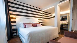 a bedroom with a white bed and a striped wall at Hills Hotel Lisboa in Lisbon