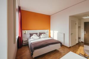 um quarto com uma cama com uma parede laranja em GZT Das Gästehaus em Tübingen