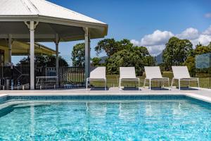 un gruppo di sedie a sdraio accanto alla piscina di The Hampton Lodge a Port Douglas