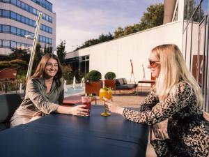 zwei Frauen sitzen an einem Tisch mit Getränken in der Unterkunft Novotel Le Havre Centre Gare in Le Havre