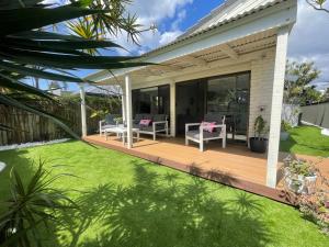 un patio con sedie bianche e erba di Seabreeze Villa on Mermaid Beach/ Broadbeach a Gold Coast