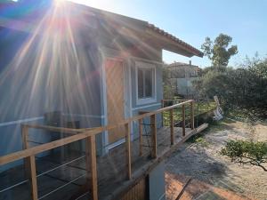 a tiny house with a porch with the sun shining on it at Tolis Rooms in Himare