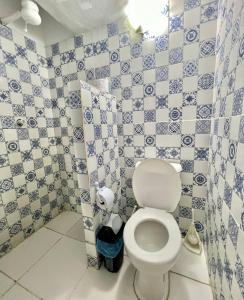 a bathroom with a toilet and a blue and white tiled wall at Pousada Cafe e Mar Jeri in Jericoacoara