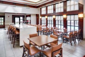 - une salle à manger avec des tables, des chaises et des fenêtres dans l'établissement Hyatt House Boston Waltham, à Waltham