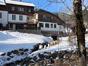 een groep bankjes in de sneeuw voor gebouwen bij Haus Frey in Altaussee