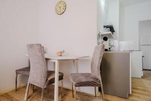 una mesa y sillas en una cocina con reloj en la pared en Apartman Sweet home, en Humenné