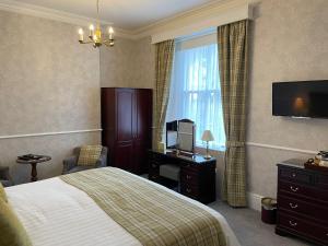 a hotel room with a bed and a television at Bryn Derwen with Private Car Park in Llandudno