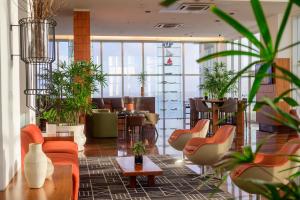 un hall avec des chaises, des tables et des plantes en pot dans l'établissement Hotel Luzeiros São Luis, à São Luís