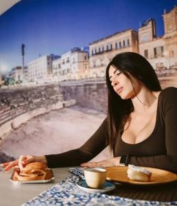 een vrouw aan een tafel met een bord eten bij "Il Vecchio Salone" appartamento in pieno centro con garage privato in Lecce