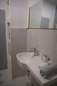 Baño blanco con lavabo y espejo en Kincses Vendégház, en Senta