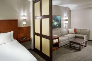 ワイオミングにあるHyatt Place Grand Rapids Southのベッドとソファ付きのホテルルーム