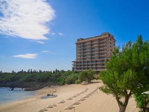 ein Strand mit Stühlen und ein hohes Gebäude in der Unterkunft Hotel Shigira Mirage Beach Front in Miyako-jima